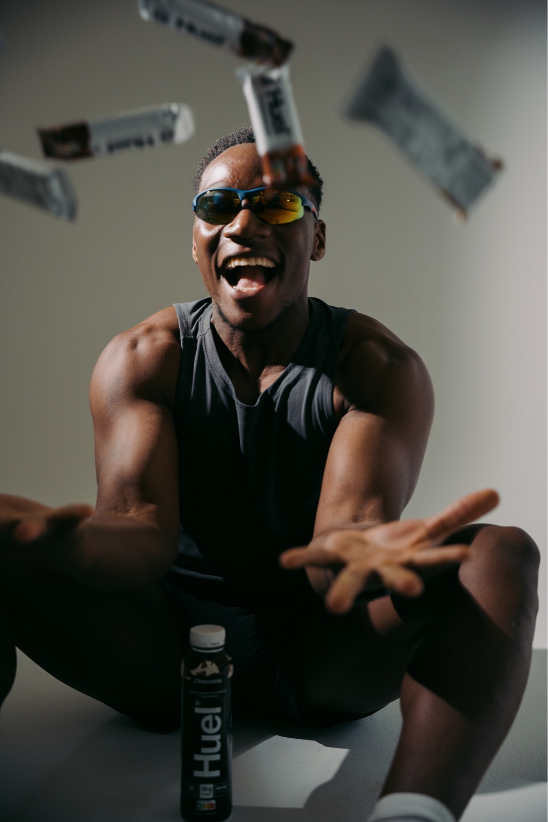 An athlete in sunglasses laughing as bars fly through the air, from an Athco Studio shoot